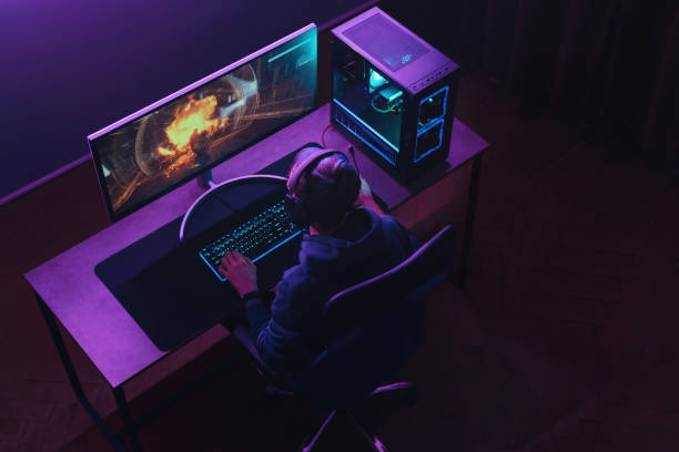 A person sits at a desk gaming on a custom-built PC with a glowing setup.